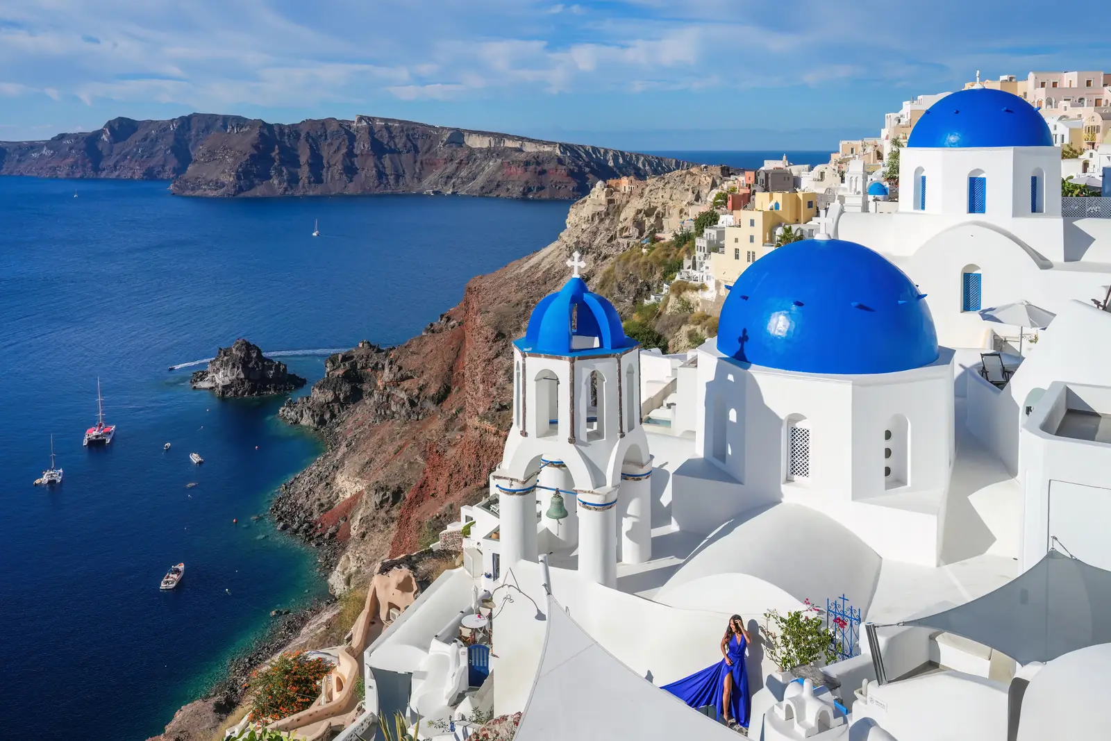 White-washed cliffside houses above the caldera in Santorini at dusk.